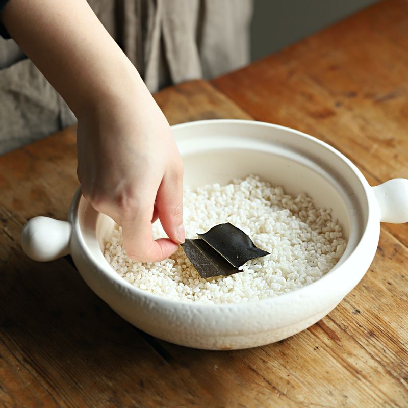 냄비에 불린 쌀과 다시마, 문어, 무를 넣고 물을 넣어주세요. 뚜껑을 닫아 중불에서 끓이다가 밥물이 끓어오르면 약불로 줄여 10~15분 정도 익혀주세요.