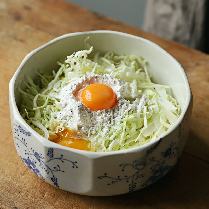 넓은 볼에 양배추를 넣고 부침가루와 달걀, 소금, 후춧가루, 물을 넣어 골고루 섞어주세요.