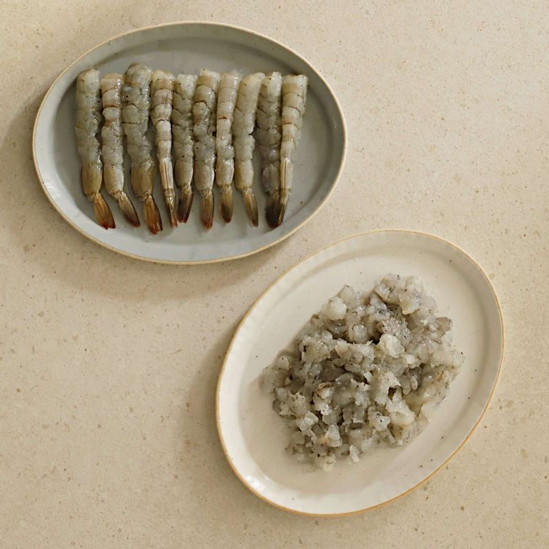 새우는 꼬리 껍질을 제외하고 머리와 몸통의 껍질을 모두 제거해주세요.
새우 내장을 제거한 후 손질한 새우는 밑간을 해둡니다
5마리는 잘게 다지고, 나머지는 배 부분에 가로로 칼집을 넣어 일자로 펴주세요.