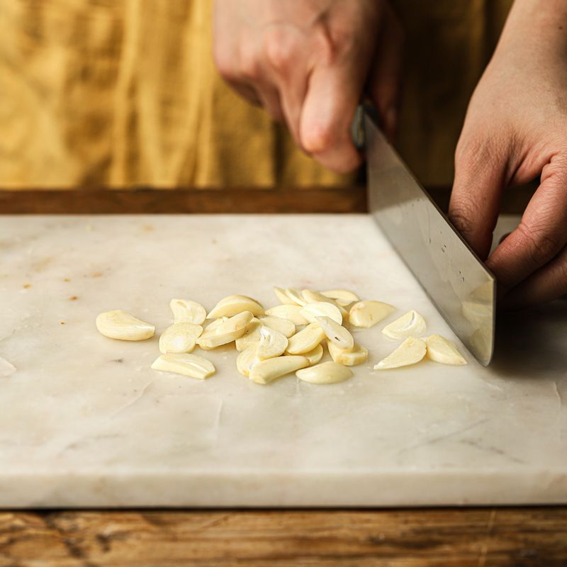 마늘은 편 썰어주세요. 달군 팬에 기름을 약간 두르고 마늘을 볶아주세요.