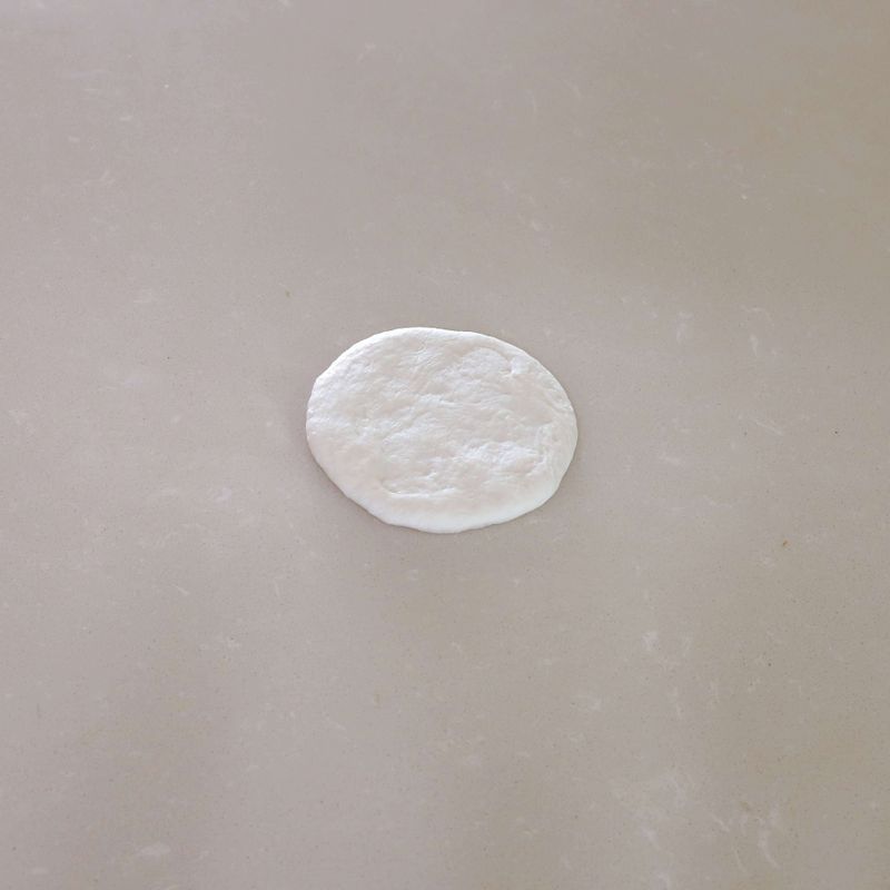 7. 반죽의 매끈한 면을 바닥에 놓고 손바닥으로 눌러 평평하게 만든 뒤 충전용 가염 버터를 넣어 이음매 부분을 꼬집어 단단히 여며주세요. 반죽의 표면이 매끈해지도록 동글리기를 해주세요.