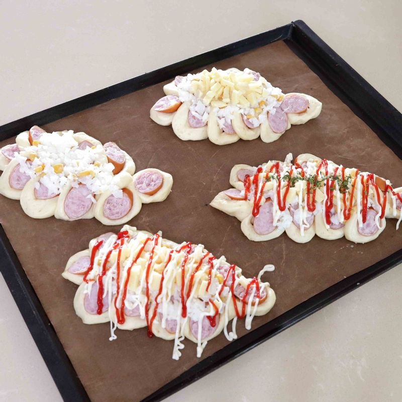 12. 마요네즈와 통조림 옥수수, 다진 양파를 버무려 순서11에 올려준 뒤 모차렐라 치즈를 뿌리고 마요네즈와 케첩, 파슬리 가루로 장식해주세요.
13. 170~180°C로 예열된 오븐에 반죽을 넣고 10~12분 정도 구워주세요.
14. 잘 익은 반죽을 오븐에서 꺼내자마자 팬을 20~30cm 높이로 들고 큰 소리가 날 정도 로 내리쳐 쇼크를 주세요. 그렇게 분리된 빵을 식힘 망에 올려 식혀주세요.