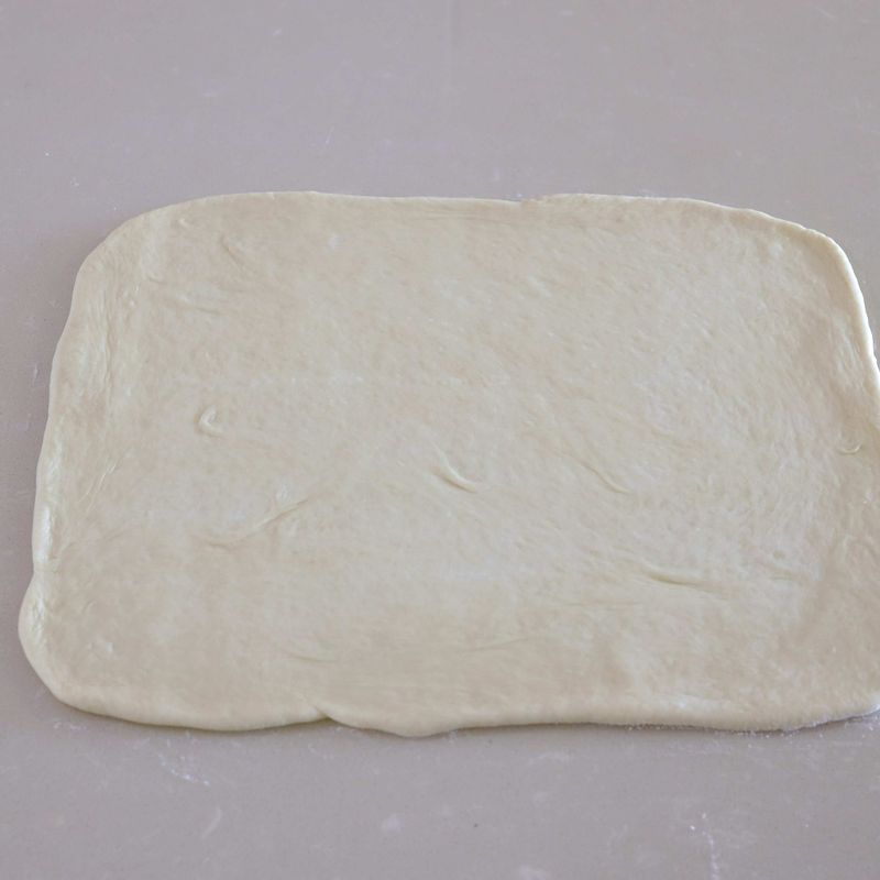 8. 작업대에 덧가루를 조금 뿌린 다음 반죽의 매끈한 면을 바닥에 놓고 가볍게 눌러 가스를 뺀 후 가로 45cm, 세로 35cm가 되도록 밀대로 밀어주세요.
9. 반죽 끝 3cm 정도를 남기고 나머지 부분에 마요네즈를 골고루 발라요.
10. 순서9에 햄과 양파, 파프리카, 피망, 옥수수 통조림, 마요네즈를 버무려 골고루 올려주세요.
11. 반죽 끝 3cm에 가볍게 물칠을 하고 돌돌 말아 이음매 부분을 꼬집어 여며준 뒤 5cm 간격으로 잘라주세요.