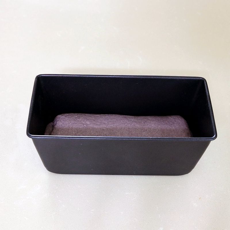 9. 팬에 반죽의 이음매가 아래로 가도록 놓은 뒤 손으로 반죽을 살짝 눌러주세요.
10. 반죽의 표면이 마르지 않도록 랩으로 덮고 2차 발효를 시작해주세요. 반죽이 팬의 약 1cm 높이까지 부푸는 것을 기준으로 합니다.