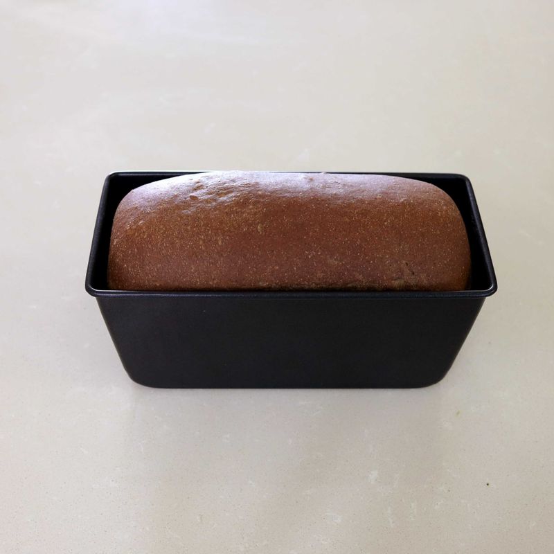 11. 170~180°C로 예열된 오븐에 반죽을 넣고 30~35분 정도 구워주세요.
12. 잘 익은 반죽을 오븐에서 꺼내자마자 팬을 20~30cm 높이로 들고 큰 소리가 날 정도로 내리쳐 쇼크를 줍니다.
13. 분리된 빵을 식힘 망에 올린 뒤 붓을 활용해 녹인 버터를 윗면에 고루 발라주세요.