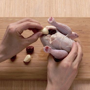 3. 손질한 닭의 뱃속에 불린 찹쌀과 통마늘, 대추를 넣어 채워주세요. 한쪽 다리 뒷편에 칼집을 넣고 다른 한쪽 다리를 X자 모양으로 교차한 뒤 칼집을 낸 부분에 끼워 고정시켜 주세요.