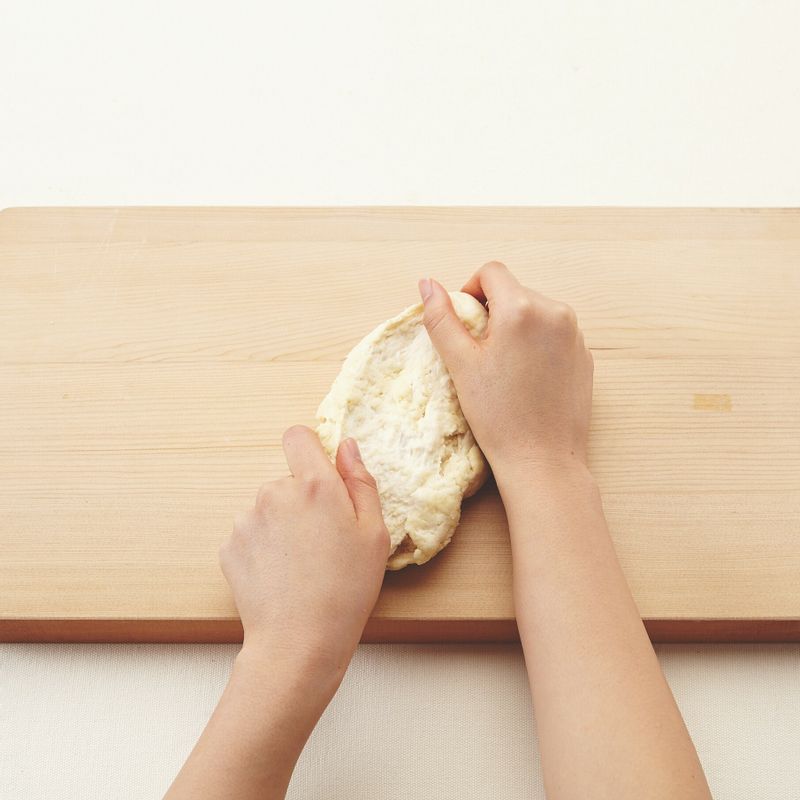 4. 반죽이 한 덩어리가 되면 도마 또는 작업대 위에 올립니다. 반죽을 양손으로 잡고 바닥에 짓이기듯이 손바닥으로 눌러 펴주세요. 다시 반으로 접어 눌러 펴며 10~15분간 반죽합니다. 버터를 넣고 5분간 더 반죽해주세요.
5. 사진처럼 양손의 날로 반죽을 살살 돌려가며 둥글리기 한 후 볼에 넣어주세요.
(tip. 볼에 녹인 버터를 살짝 발라주면 발효 후 반죽이 잘 떨어져요.)
6. 큰 볼에 뜨거운 물을 넣고 그 위에 순서5의 볼을 올린 후 랩을 씌웁니다. 따뜻한 곳(28~30℃)에서 20분간 1차 발효시켜주세요.