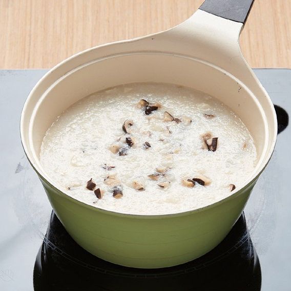 2. 달군 냄비에 참기름을 두른 뒤 불린 건표고버섯을 넣고 볶다가 물과 밥을 넣어 끓여주세요. 끓어오르면 국간장을 넣고 중불로 중간중간 저어가며 8~10분간 끓여주세요.
