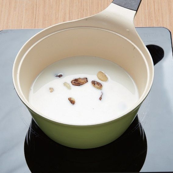 3. 냄비에 구운 마늘과 불린 찹쌀, 우유, 물을 넣고 끓여주세요. 끓어오르면 중불로 낮추고 생크림을 넣어 찹쌀이 푹 익도록 더 끓여줍니다.