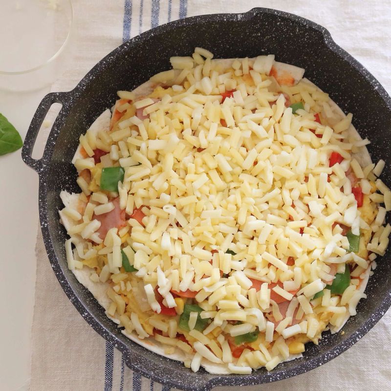 토르티야를 찢어서 팬 위에 깔고 토마토소스, 고구마 메시, 야채, 치즈 순으로 덮어주세요.