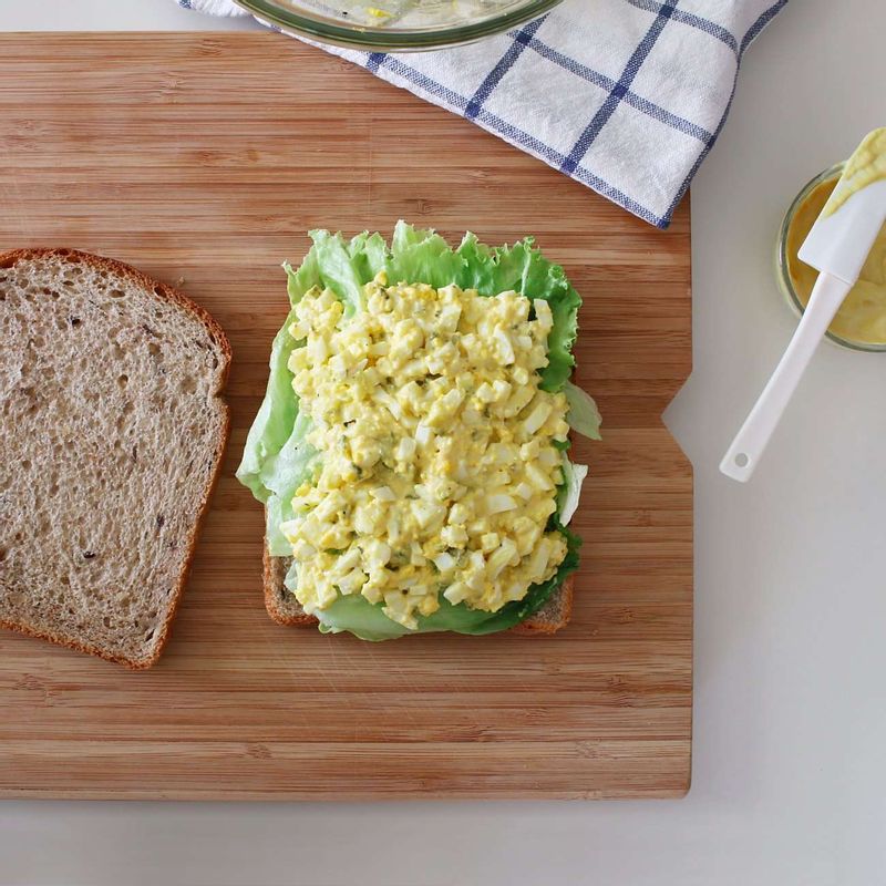 스프레드 재료를 섞어 빵 한 쪽에 바른 후 양상추-STEP3-적양파-토마토-무순 순으로 올려주세요. 빵으로 덮고 가볍게 누른 후 반으로 잘라주세요.