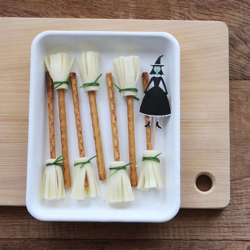 데코용으로 치즈 빗자루도 만들어보세요.
슬라이스 치즈를 4등분으로 자른 후, 치즈 윗부분을 1센치 정도 남기고 칼집을 촘촘히 넣어주세요. 칼집이 들어가지 않은 치즈 윗부분으로 긴 막대과자를 돌돌 감싸고, 살짝 데친 영양부추로 묶어주세요.