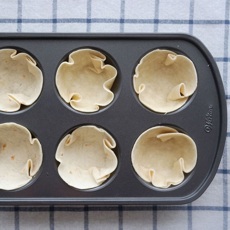 찍어낸 토르티야를 머핀 틀에 넣어 컵 모양으로 깔고 떡볶이, 옥수수, 피자치즈 순으로 올려 채워주세요.