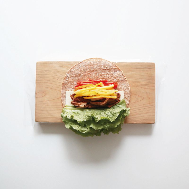 랩을 깔고 구운 통밀또띠아를 올려요. 슬라이스 치즈, 닭가슴살 장조림, 파프리카, 청상추를 올려주세요.