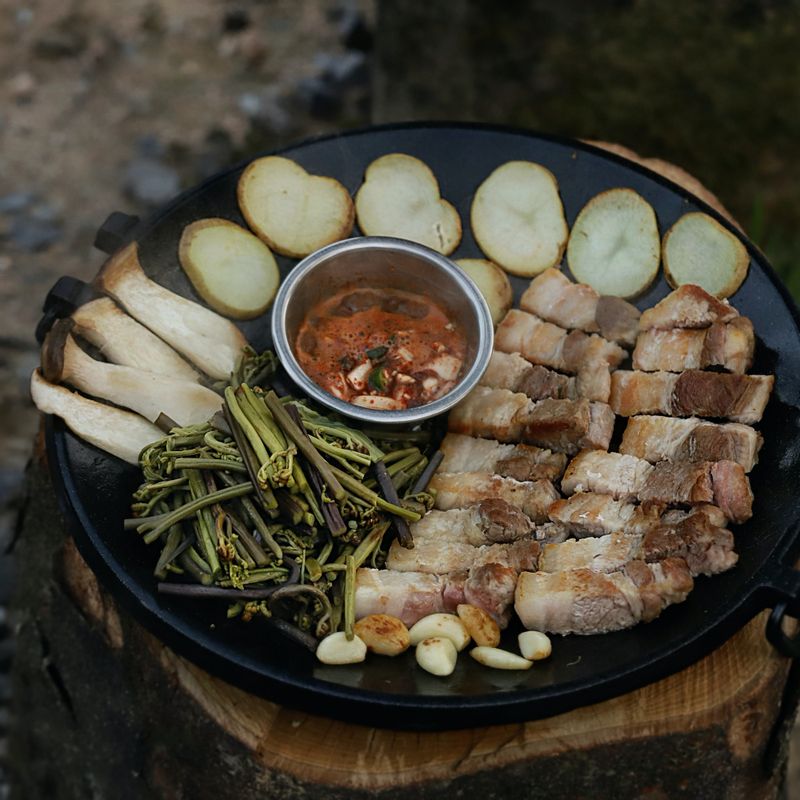 달군 팬에 삼겹살과 생고사리, 새송이버섯, 감자, 마늘을 노릇하게 구워주세요. 팬에 멜젓 소스를 끓여가며 맛있게 즐겨주세요.
