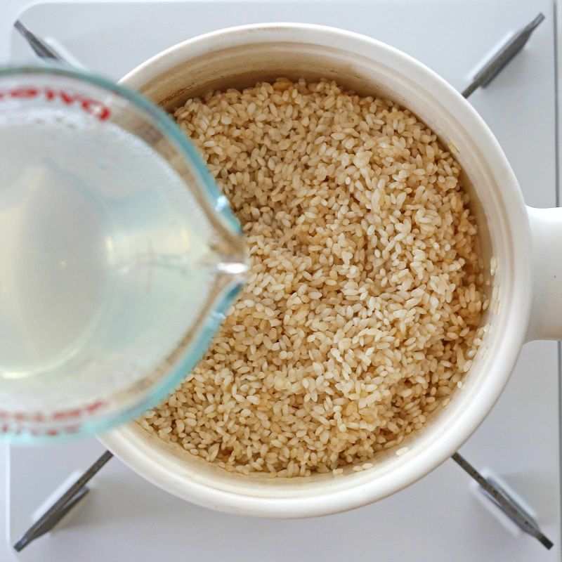 달군 솥에 참기름 1큰술을 두르고 불린 쌀과 양조간장 1큰술을 넣어 볶다가, 바지락 삶은 물 300ml를 넣고 중간 불에서 5분 가량 가열해주세요.