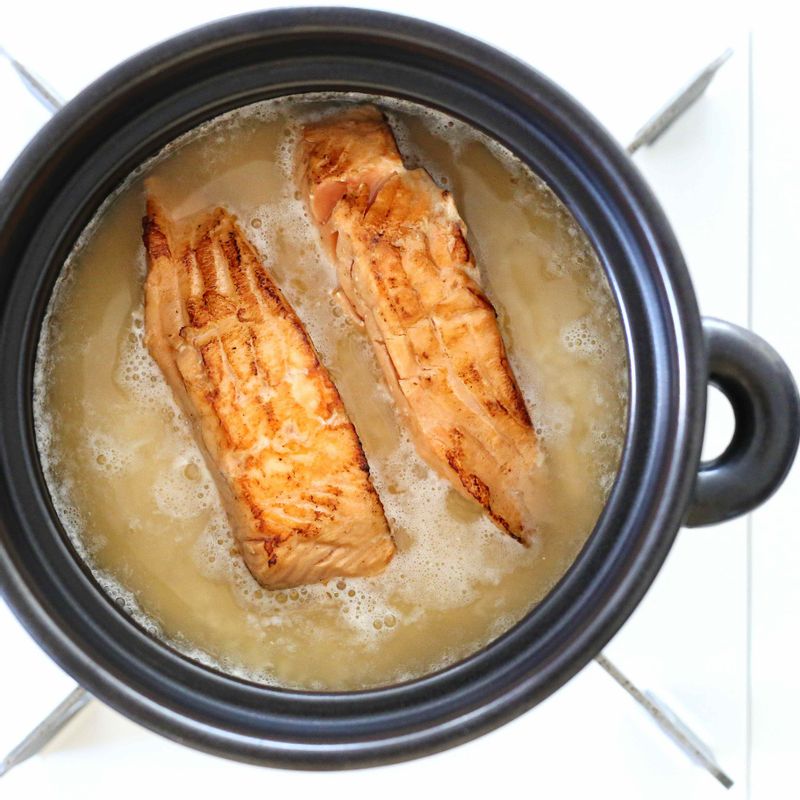 다시마 냉침 육수 300ml를 붓고 그 위에 연어를 올려 센 불에서 5분간 끓여주세요. 끓어오르면 약한 불로 줄여 10분간 가열합니다.