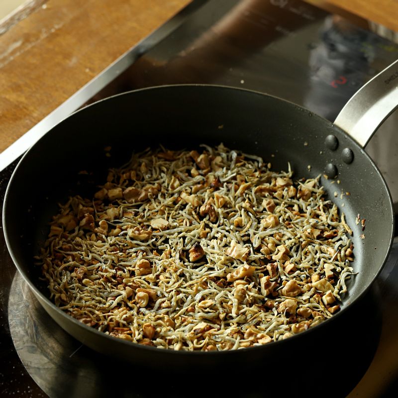 달군 팬에 올리브 오일을 두른 후 잔 멸치와 견과류를 넣어 볶아주세요. 멸치가 볶아지면 불을 끈 후 멸치 양념 재료를 넣어 고루 섞어주세요.