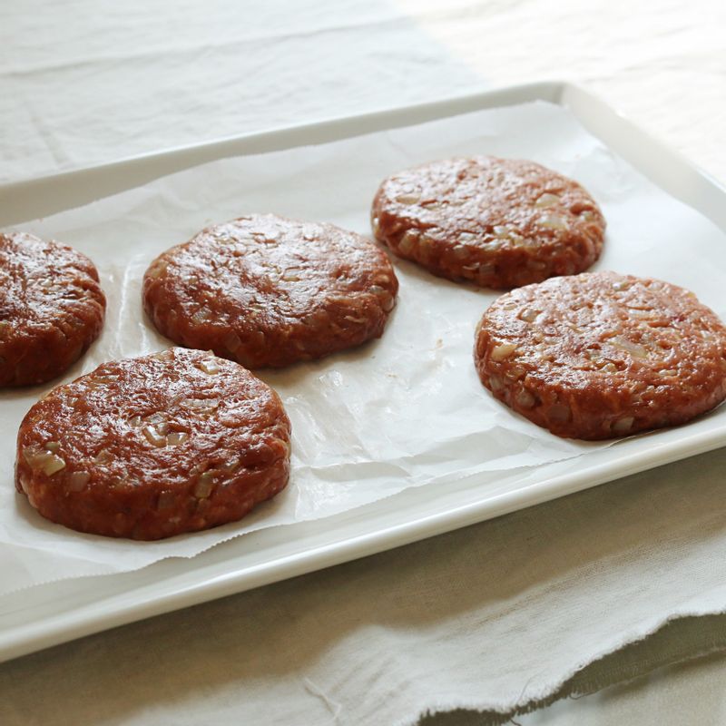 반죽을 동그랗게 빚은 후 모닝빵 크기보다 조금 더 큰 크기로 납작하게 눌러 패티를 완성합니다.