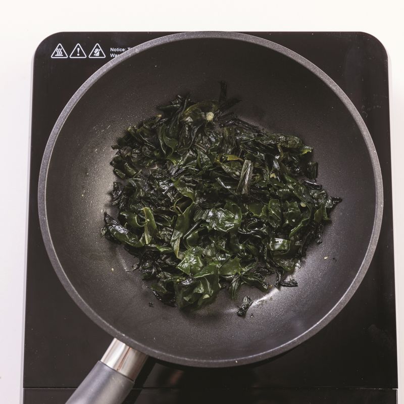 오목한 팬에 미역과 다진 마늘, 다진 생강, 들깨가루, 들기름과 국간장을 넣고 중불에서 4분간 볶아주세요.