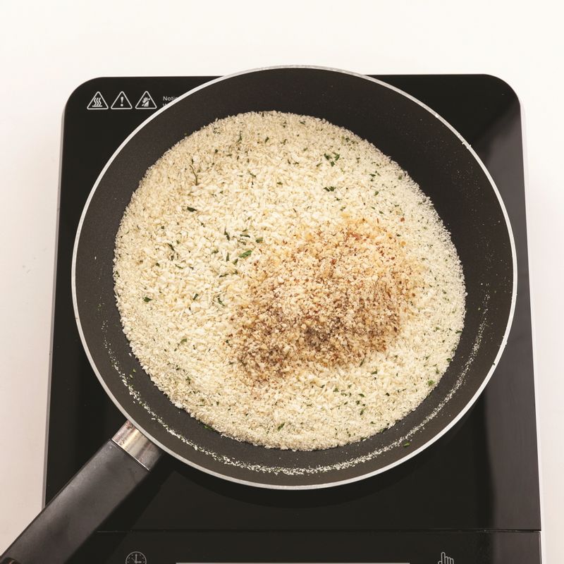 달군 팬에 빵가루를 넣고 약불에서 1분 볶은 뒤 파슬리, 잘게 부순 견과류를 넣고 2분간 볶아주세요.