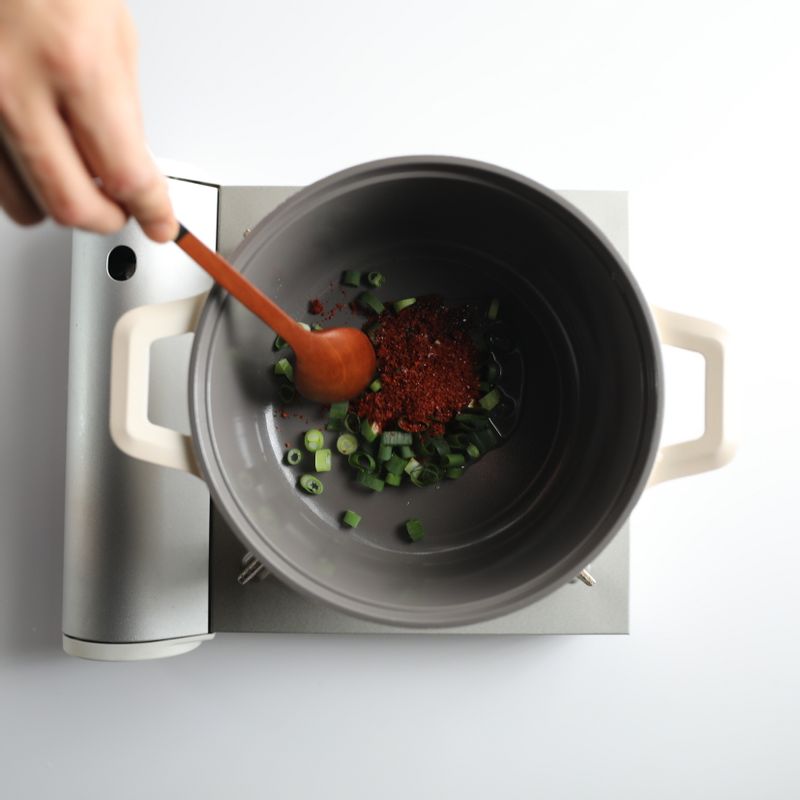 약불로 달군 냄비에 식용유를 두르고 대파와 고춧가루를 넣어 1분 정도 볶아 고추기름을 내주세요.