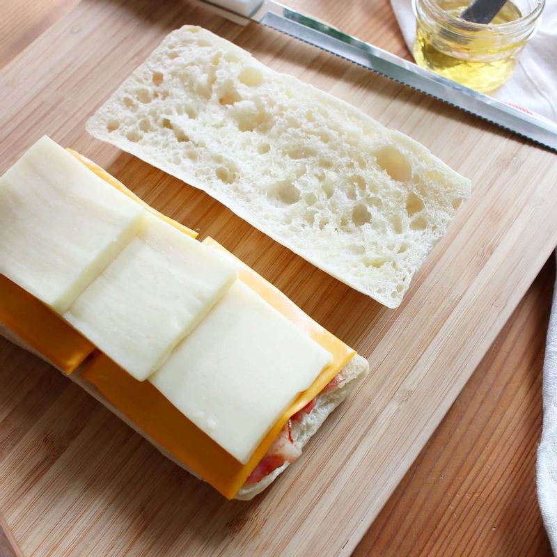 치아바타를 반으로 갈라 빵의 양면에 꿀을 발라주세요. 베이컨-슬라이치즈-모차렐라치즈 순으로 얹은 후 빵으로 덮어주세요.