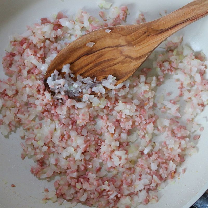 달군 팬에 식용유를 두르고 양파와 베이컨을 2분간 볶아주세요.