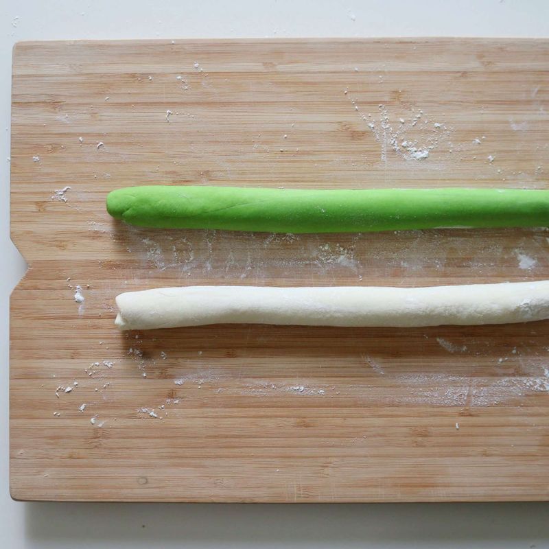 흰색 만두피 반죽과 시금치 만두피 반죽을 각각 길게 민 후, 시금치 만두피 반죽으로 흰색 만두피 반죽을 감싸주세요.