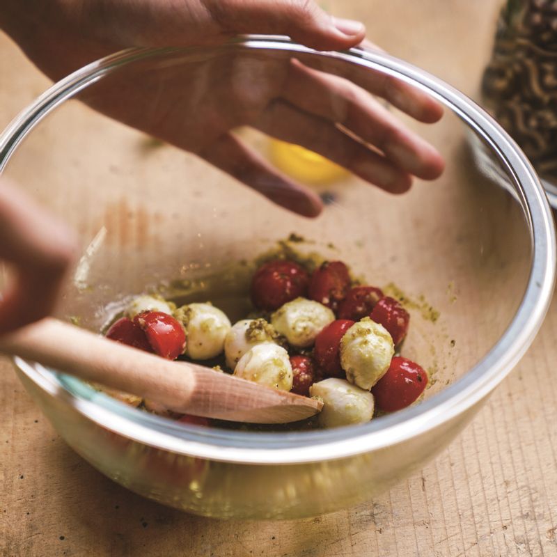 믹싱 볼에 반으로 자른 방울토마토, 보코치니 치즈, 바질 페스토, 다진 마늘, 올리브유, 소금, 후추를 넣고 골고루 섞어주세요.