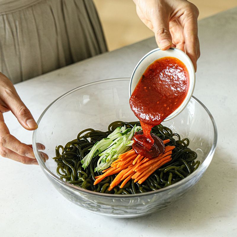 그릇에 미역 국수와 썰어 둔 야채를 담고 비빔소스를 넣어 골고루 섞어주세요.
(비빔소스가 없을 경우 고추장 2큰술, 간장 1큰술, 설탕 2큰술, 다진 마늘 1작은술, 식초 1큰술, 참기름 약간, 통깨, 후춧가루 약간을 넣어 섞어 양념장을 만들어 사용해주세요)