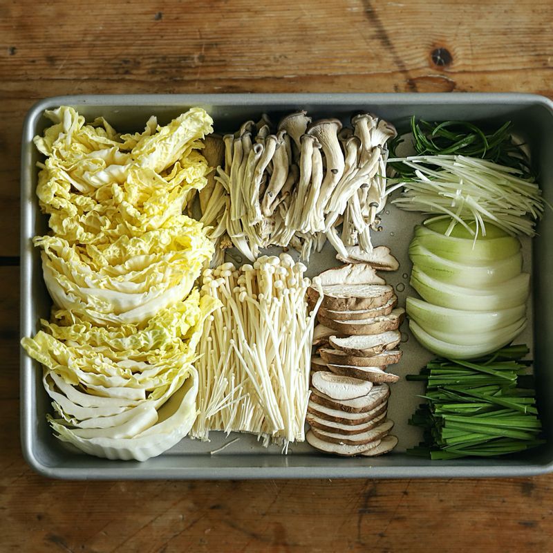 배추는 한입 크기로 자르고 느타리버섯은 먹기 좋게 가닥가닥 찢어내어 준비해 주세요. 대파는 얇게 채를 썰고, 부추는 6cm 길이로 썰어주세요. 팽이버섯은 밑동을 제거하고 표고버섯과 양파는 채를 썰어 주세요.