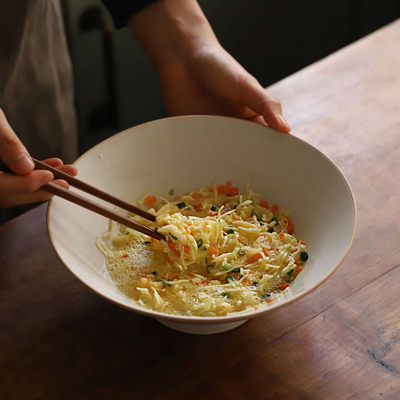 볼에 달걀 3개와 소금, 설탕, 후추를 넣고 잘 푼 후 당근, 양파, 실파, 양배추를 넣어 고루 섞어주세요.