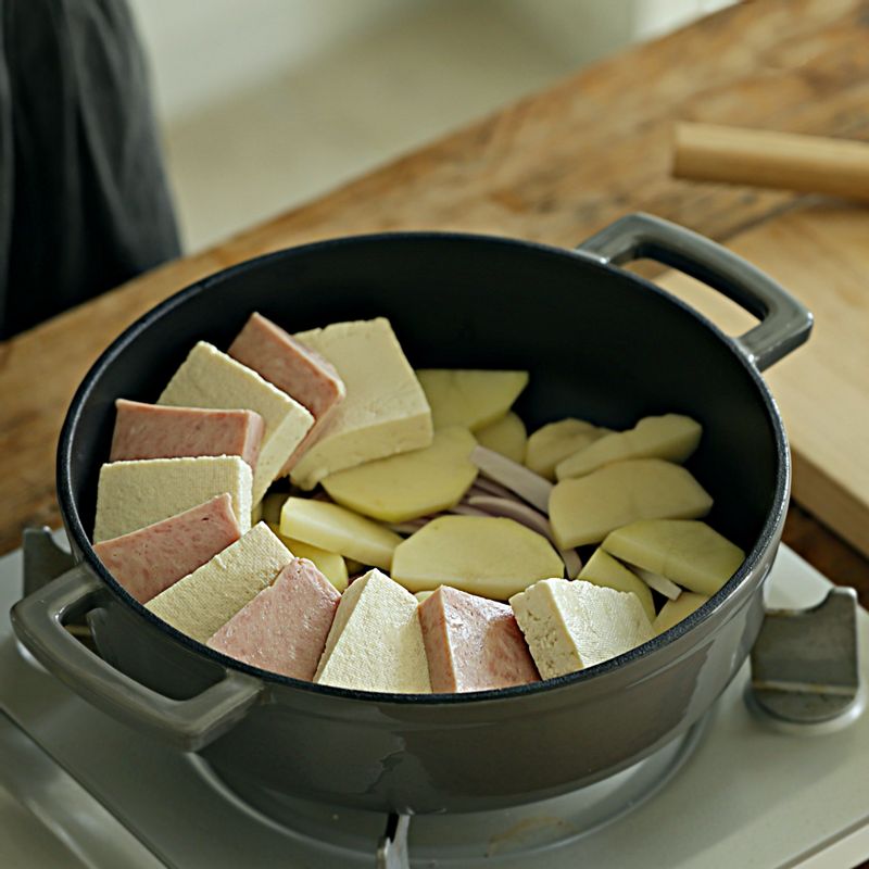 냄비에 양파를 깔고 감자를 올린 후 두부와 스팸을 켜켜이 돌려가며 담아주세요.