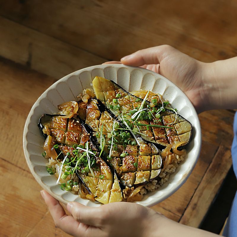그릇에 밥을 담고 덮밥 소스를 끼얹은 후 구운 가지를 올리고, 통깨와 쪽파를 뿌린 후 맛있게 즐겨주세요.