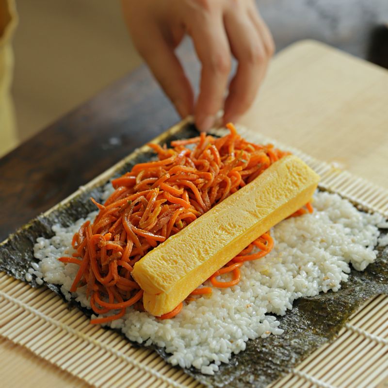 김밥 김에 밥을 얇게 펼치고 볶은 당근과 달걀을 넣고 말아주세요.