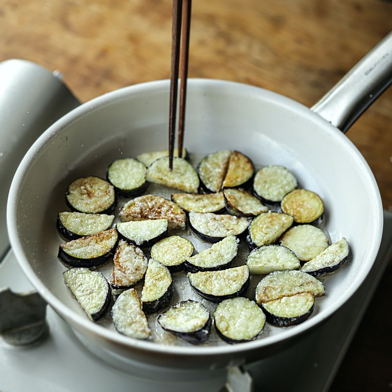 달군 팬에 오일을 두른 후 전분을 묻힌 가지를 넣어 노릇하게 구워주세요.