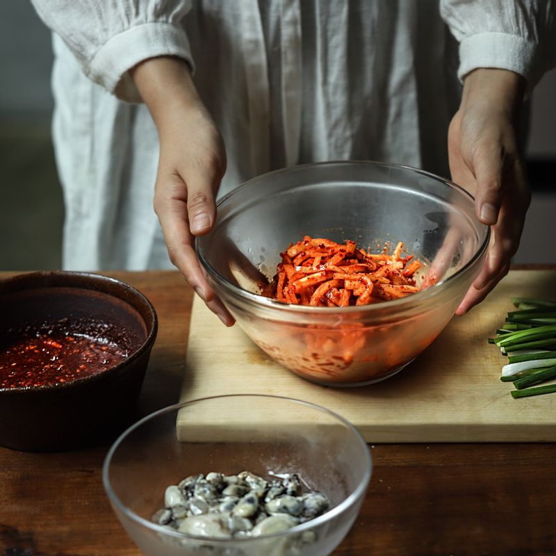 굴은 옅은 소금물에 살살 헹군 후 체에 밭쳐 물기를 제거합니다. 무채는 굵은 소금에 10분간 절였다가 물기를 제거하고 고춧가루를 넣어 무쳐주세요.