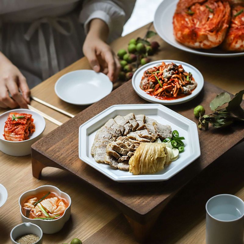 돼지고기를 건져 한입 크기로 도톰하게 썰고 통깨를 뿌려주세요. 굴무침, 알배추 잎을 곁들여 냅니다.