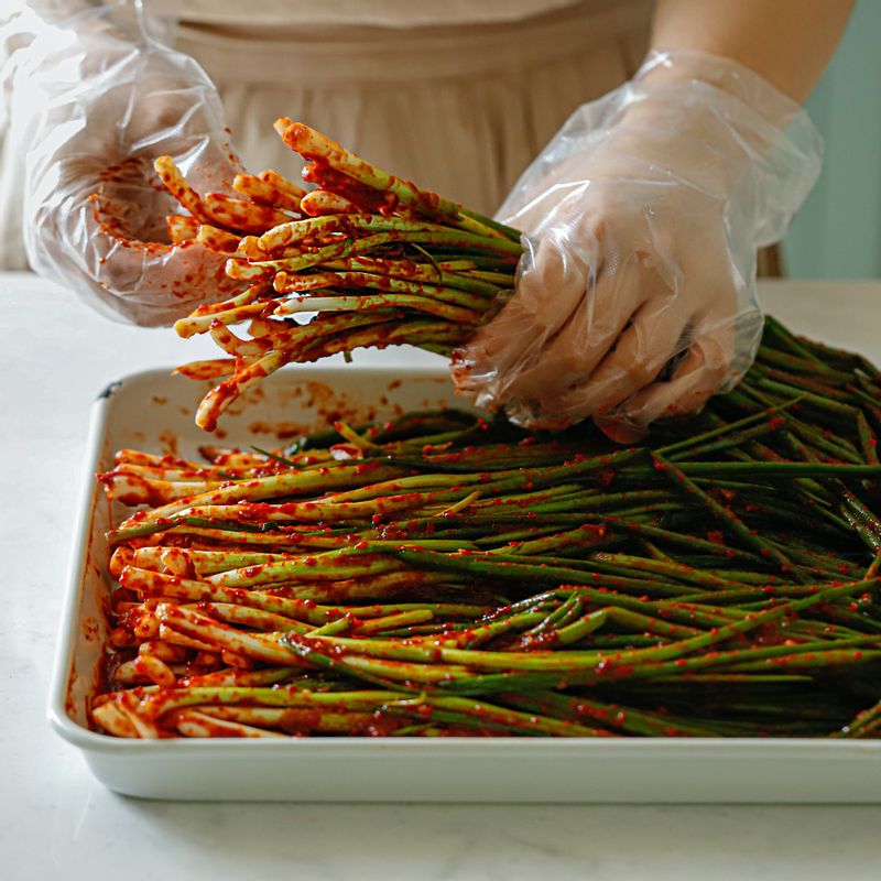 쪽파에 김치 양념을 뿌리 쪽부터 잎 쪽으로 고루 펴 발라주세요.