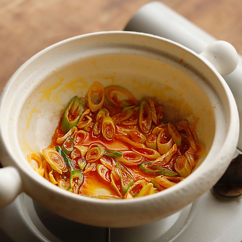 냄비에 고추기름과 대파 반을 넣고 중약불에서 달달 볶다가 파 향이 올라오면 양파, 김치 순서로 넣어 볶아주세요.