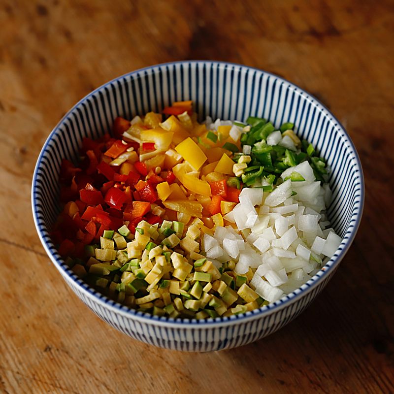 그릇에 밥을 담고 잘게 썬 애호박과 양파, 청양고추, 파프리카를 올려주세요.
