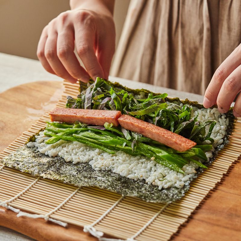 김에 밥을 고르게 펼친 후 스팸, 청양고추, 깻잎을 올려 단단하게 말아주세요.
(tip.속 재료는 크래미, 참치 등 집에 있는 재료를 응용 해도 좋아요)
(tip.밥의 끝과 김이 맞닿게 말면 더욱 예쁘게 만들 수 있어요)