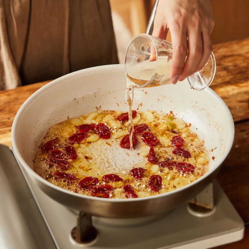 화이트와인을 넣고 끓이다가 선드라이 토마토를 넣어 볶아주세요.