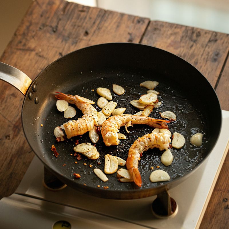 팬에 올리브오일을 두르고 마늘 편과 페페론치노를 넣어 약간의 소금과 후추로 밑간하여 볶아주세요. 손질한 새우를 넣어 마늘이 노릇해질 때까지 볶아주세요.