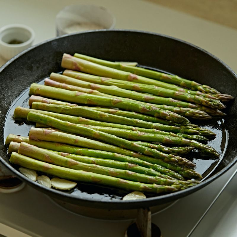 달군 팬에 올리브오일을 두르고 편 썬 마늘과 아스파라거스를 넣고 소금과 후추를 뿌려 센 불에서 굽다가 뚜껑을 닫아 4~5분간 중약 불로 익혀주세요.