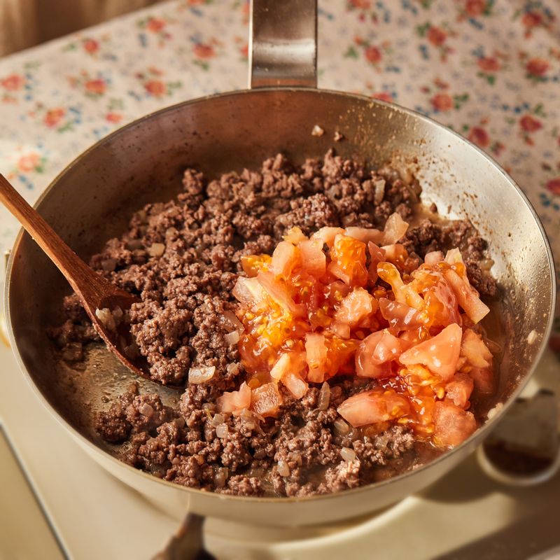 속을 파낸 토마토 속을 4큰술 정도 넣어 같이 볶아주세요. 볼에 볶은 소스를 담은 후 빵가루와 다진 파슬리, 파마산 치즈가루를 넣어 섞어주세요.