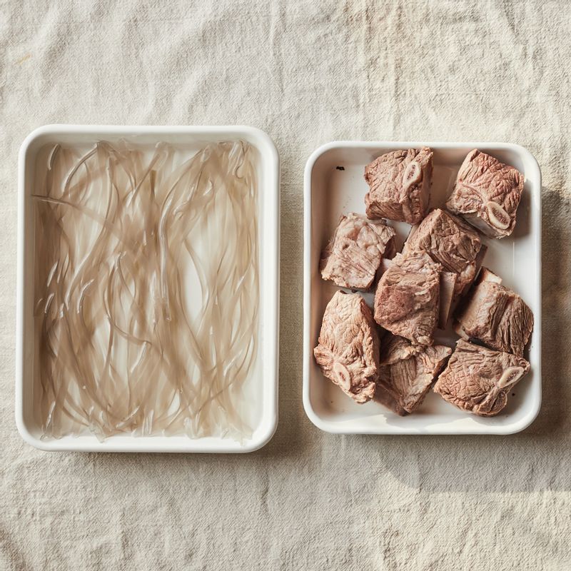 갈비는 찬물에 담가 핏물을 빼고 끓는 물에 데친 후 찬물에 헹궈 기름을 떼 내어 손질해주세요. 납작 당면은 찬물에 30분 이상 불려 준비해주세요.