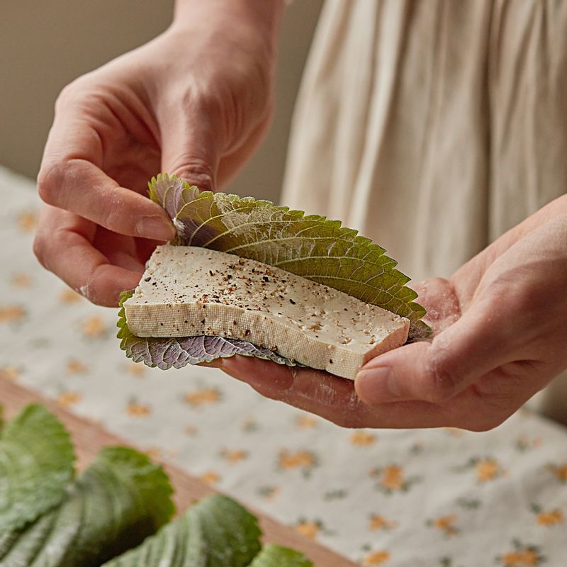 깻잎 안쪽에 부침가루를 묻혀 가볍게 털고 두부를 얹은 후 깻잎을 반으로 접어주세요. 깻잎 앞뒤에 부침가루를 묻혀 살짝 털어내고 강황물을 고루 입혀주세요. 볼에 초간장 재료를 섞어주세요.