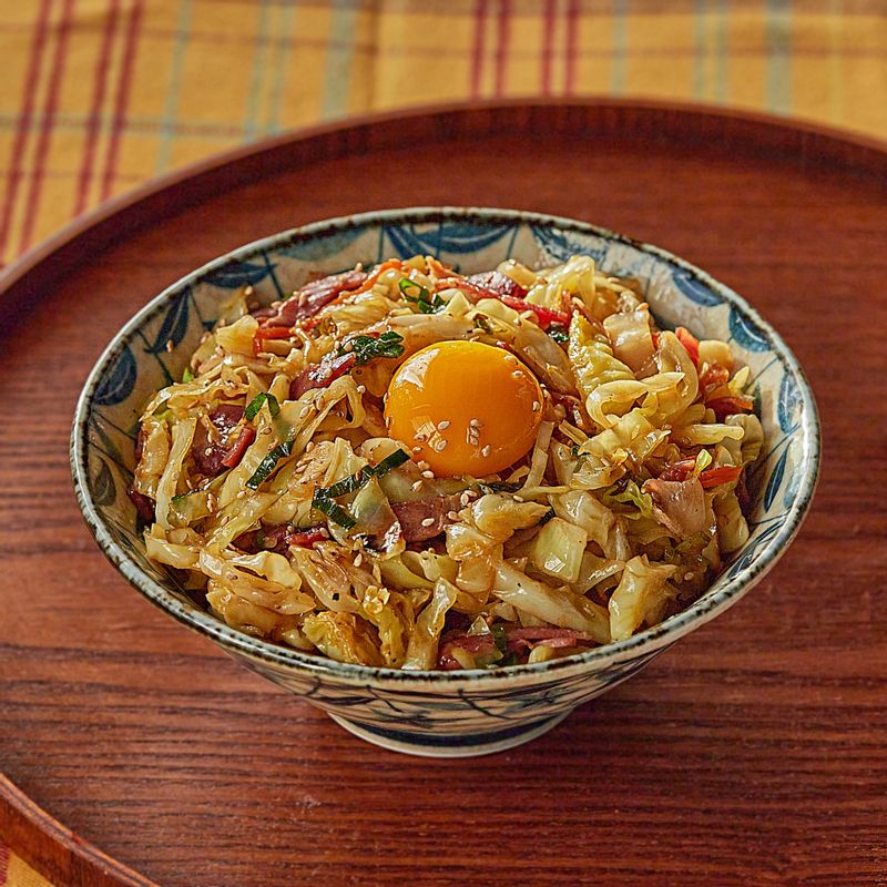 그릇에 밥을 담은 후 양배추 볶음을 얹은 후, 가운데 달걀을 올려 참기름과 통깨를 뿌린 후 완성해 주세요.